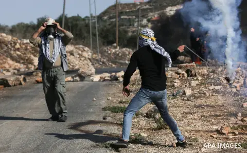 A Palestinian protester returns a tear gas canister during clashes following a weekly demonstration against the expropriation of Palestinian land by Israel in the village of Kfar Qaddum, near the West Bank city of Nablus...