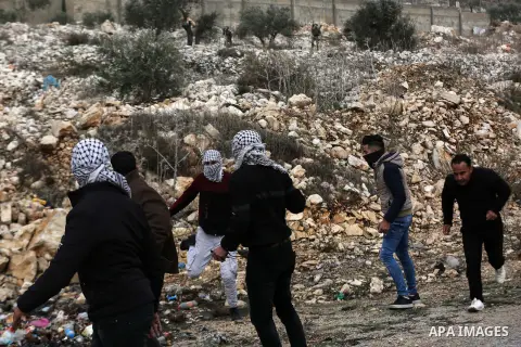 A Palestinian protester hurls a stone towards Israeli security forces during clashes following a weekly demonstration against the expropriation of Palestinian land by Israel in the village of Kfar Qaddum, near the West B...