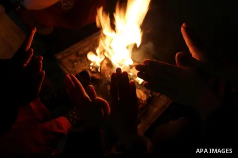 Palestinians warm themselves by a fire during a rainy day in Dair Al Balah in the center of Gaza strip on December 15, 2019. Photo by Ashraf Amra