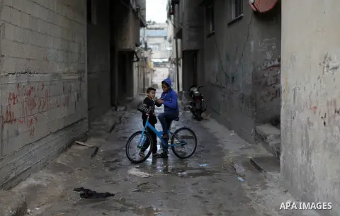 Palestinians walk in a street during a rainy day in Gaza city on December 15, 2019. Photo by Mahmoud Ajjour