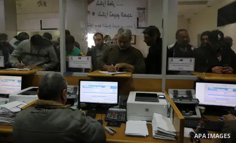 Palestinians wait to receive their financial aid outside the Post Office, in Gaza city, on December 24, 2019.The Qatar grant on Wednesday began disbursing $100 to Poor Families. Photo by Ashraf Amra