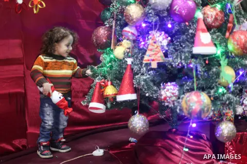 A Palestinian child stands next to the Christmas tree decorated with remants of the environment, in Gaza city on December 26, 2019. Photo by Mahmoud Ajjour