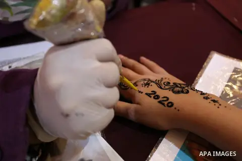 A Palestinian woman applies henneh herbal tattoo on the hand of a young girl during an exhibition of local traditional crafts, made by Palestinian women in Gaza City on December 31, 2019. Photo by Ashraf Amra
