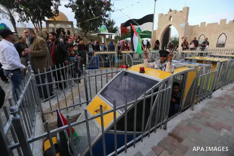 A Palestinian man holding a Palestinian flag enjoys a ride in an amusement park suspension railway dubbed "Train of Return" in Khan Youns southern in Gaza city January 2, 2020. Photo by Ashraf Amra
