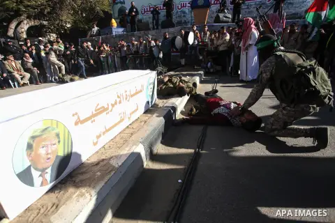 Palestinian Hamas supporters lay down beside a model of a coffin representing the U.S. embassy in Jerusalem with a picture of U.S. President Donald Trump and Israeli Prime Minister Benjamin Netanyahu, during a rally in G...