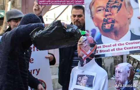 Palestinian protesters hold banners during burn effigies depicting U.S. President Donald Trump and Israeli Prime Minister Benjamin Netanyaho in the West Bank city of Hebron, on February 28, 2020. Photo by Mosab Shawer