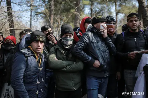A picture taken on March 1, 2020. Refugees sit in a field near the Pazarkule gate in Edirne region, at the Turkish-Greek border. Migrants and refugees hoping to enter Greece from Turkey appeared to be fanning out across...