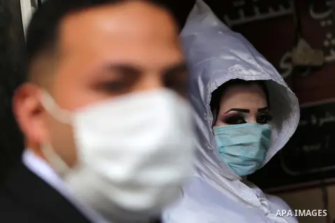A Palestinian bride and groom wearing masks as a preventive measure against the coronavirus disease leave a hairdressing salon, on their wedding day in Khan Younis in the southern of Gaza strip, on March 22, 2020. Author...