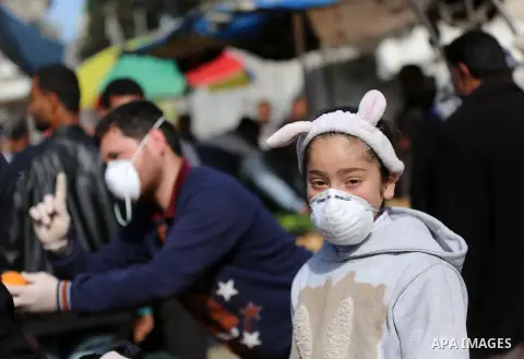 Palestinian girl wearing a mask stands in Jabalia Market, northern Gaza Strip, on March 26, 2020, amid the novel coronavirus pandemic. Photo by Ashraf Amra