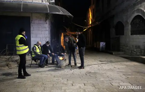 Palestinians guard the closed shops and streets at night, during of a "mandatory quarantine" that was announced by the Palestinian Authority as part of measures against the COVID-19 coronavirus pandemic, in the old city...