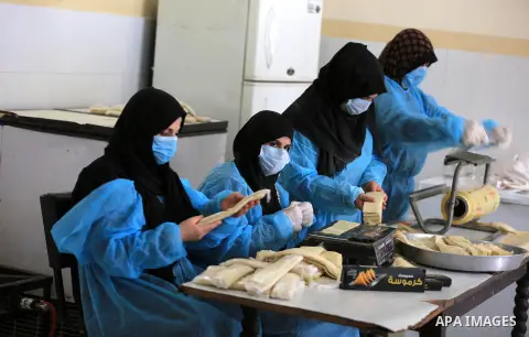 Palestinian women wear protective, make samosa and Kubba, to receive the Islamic holy month of Ramadan , as precaution against the coronavirus disease (COVID-19), in Khan Younith in the southern Gaza Strip on April 18, 2...