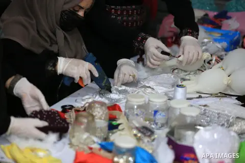 Palestinian women make masks, especially for celebrations, by the cloth and accessories as a precaution against the spread of the coronavirus disease (COVID-19), in Khan Younis in the southern of Gaza strip on April 21,...