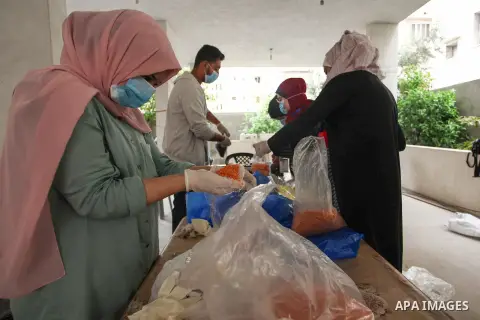 Palestinian volunteers wearing a face mask and gloves prepare food parcels to poor families during the holy fasting month of Ramadan in Gaza City on April 24, 2020. Muslims around the world celebrate the holy month of Ra...