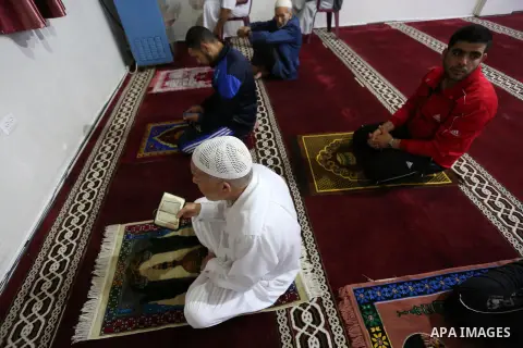 Palestinians perform the dawn prayer (salat al-fajr) in a mosque as the holy places reopen to worshippers to perform the weekly Islamic ritual, amid concern about the spread of the coronavirus disease (COVID-19), in Deir...