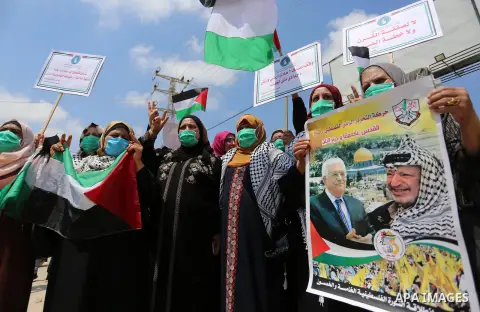 Palestinian women hold placards and national flags during a demonstration against Israel's West Bank annexation plans in front of the gate of Erez crossing with Israel in Beit Hanoun in the northern Gaza Strip, on July 6...