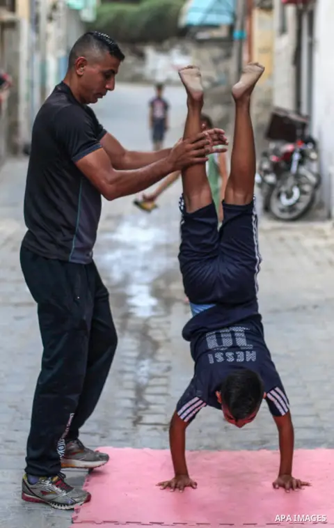Palestinian parkour trainer Ahmed Abu Hasira "myuz",35, trains children outside his home, in Gaza City on August 18, 2020. Parkour is an activity that can be practiced alone or with others and is usually carried out in u...