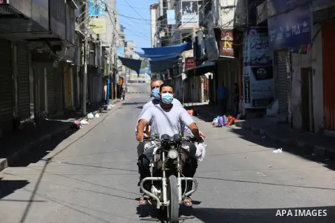 Palestinians wear face masks as they walk in a street during a 48 hour lockdown imposed following the discovery of the first coronavirus cases in the Gaza Strip, in Khan Younis in the southern Gaza strip August 25, 2020....