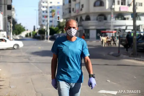 Palestinians wear face masks as they walk in a street during the imposed lockdown to mitigate virus outbreak in the Gaza Strip, in Gaza city on September 2, 2020. Photo by Mahmoud Ajjour