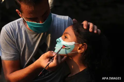Palestinian painter Osama Abu Hamra, paints masks on children's faces on the rubble of a destroyed home during a lockdown following the outbreak of the coronavirus disease (COVID-19), in Gaza city, on September 8, 2020....