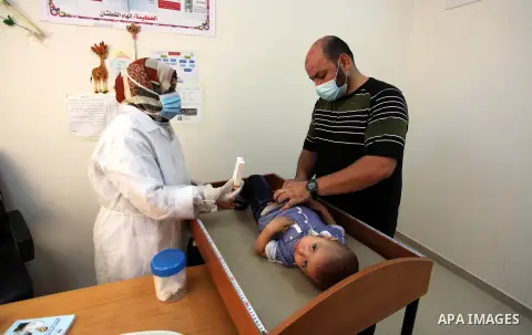 A UNRWA employee wears face mask as she provides Polio vaccine and Rota virus vaccines for children in a clinic in Bureij refugee camp central of Gaza Strip on September 9, 2020. Photo by Mahmoud Ajjour