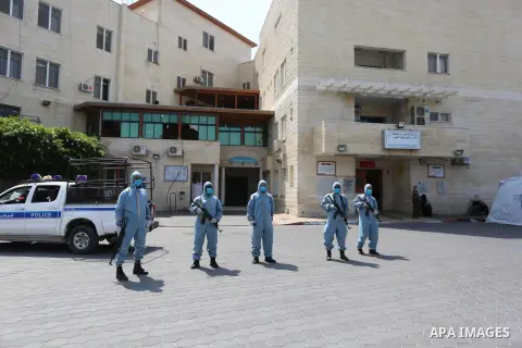Palestinian policemen wearing protective gear, guard a barrier blocking a road, in Deir Al-Balah, in the center of the Gaza Strip, on Sept. 10, 2020, during a lockdown amid the COVID-19 pandemic. Photo by Ashraf Amra