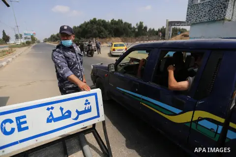 Palestinian policemen wear face masks, guard a barrier blocking a road, in Deir Al-Balah, in the center of the Gaza Strip, on Sept. 10, 2020, during a lockdown amid the COVID-19 pandemic. Photo by Ashraf Amra