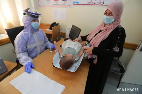A UNRWA employee wears face mask as she provides Polio vaccine and Rota virus vaccines for children in a clinic, in Deir Al-Balah, in the center of the Gaza Strip, on Sept. 10, 2020 Photo by Ashraf Amra