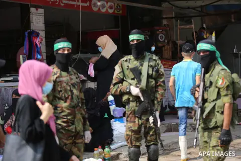 Palestinian members of al-Qassam Brigades, the armed wing of the Hamas movement, distribute protective masks to people on the street amid the Covid-19 coronavirus pandemic, in Nuseirat in the central of Gaza Strip on Sep...