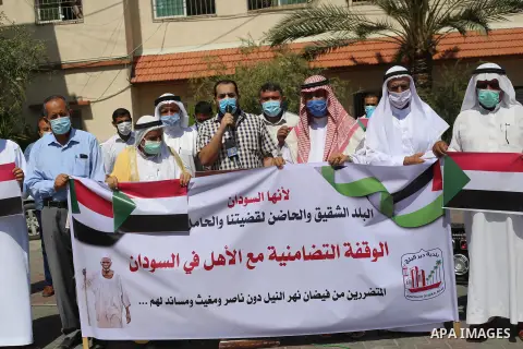 Palestinian men carry banners during a solidarity with the Sudanese people in Deir Al-Balah in central Gaza strip on Septemper 13, 2020. Photo by Ashraf Amra