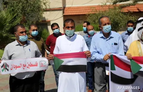 Palestinian men carry banners during a solidarity with the Sudanese people in Deir Al-Balah in central Gaza strip on Septemper 13, 2020. Photo by Ashraf Amra