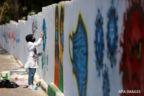 Palestinian artists paint a coronavirus awareness and against normalization mural, in Deir Al-Balah, in the central Gaza Strip on Septemper 16, 2020. Photo by Ashraf Amra