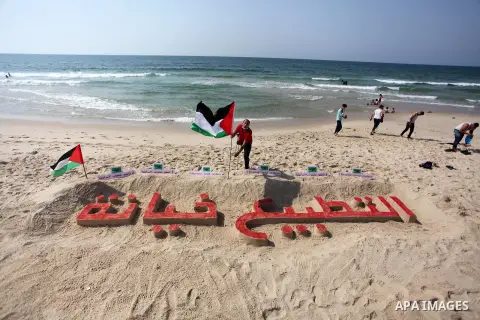 Palestinians paint on the sand sculpture titled "normalization is betrayal", at the beach of Gaza city, on September 16, 2020. The decision by the UAE and Bahrain to normalise ties with Israel breaks with decades of cons...