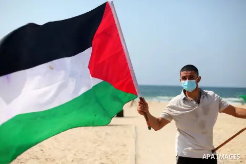A Palestinian youth holds the flag of Palestine on the beach of Gaza city, on September 16, 2020. The decision by the UAE and Bahrain to normalise ties with Israel breaks with decades of consensus within the Arab world t...