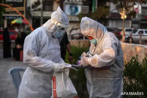 Palestinian doctors wearing protective gear, take a swab sample from a man in a public park, during a COVID-19 screening campaign in Gaza city, on Sept. 20, 2020. Photo by Mahmoud Ajjour