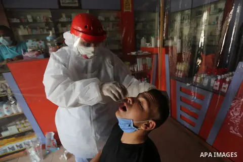 A Palestinian midical wearing protective gear, takes a swab sample from a man during a COVID-19 screening campaign in Deir Al-Balah, in the central Gaza Strip, on Sept. 21, 2020. Photo by Ashraf Amra
