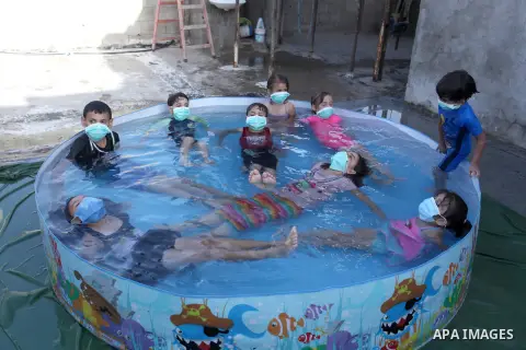 Palestinian children wear face masks play together as they cool off in the water in a metal frame pool erected on the rooftop of a residential building, amid the spread of the coronavirus pandemic, in Gaza City on Septem...