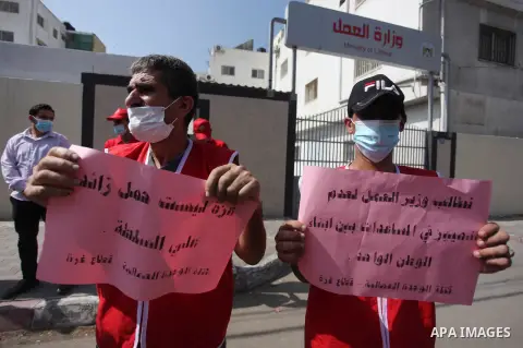 Palestinian workers hold placards during a protest to demand their rights, outside the Ministry of Labor headquarters in Gaza city on September 29, 2020. Photo by Mahmoud Ajjour