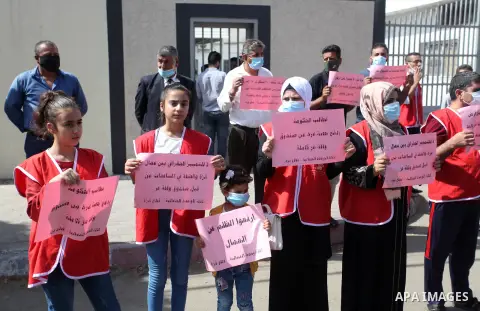 Palestinian workers hold placards during a protest to demand their rights, outside the Ministry of Labor headquarters in Gaza city on September 29, 2020. Photo by Mahmoud Ajjour