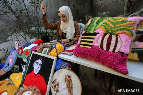 Palestinian plastic artist Aya Maghari, 22, embroiders with wool, geometric shapes, paintings and figures using a special embroidery needle, in the garden of her home in Nuseirat in the central of Gaza Strip, on November...