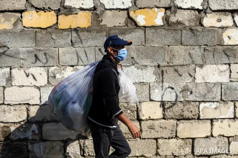 A young Palestinian wear a face mask carry a bag of scrap is walks down an alley in Gaza City, on December 2, 2020. The Israel-led blockade of the Gaza Strip cost the Palestinian enclave more than $16bn and pushed more t...
