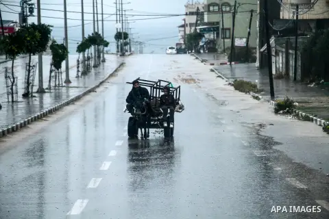 Palestinians walk in a street flooded by rain water during a rainy day, in the northern Gaza Strip, on December 16, 2020. Occasional rain showers, which could be torrential, along with occasional thunderstorms are expect...