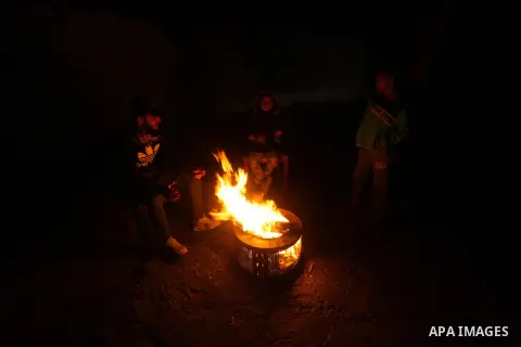 Palestinians warm themselves by a fire during a rainy day in Gaza city, on December 16, 2020. Occasional rain showers, which could be torrential, along with occasional thunderstorms are expected in the daytime, and will...