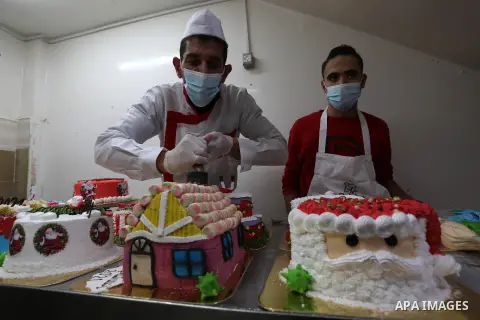 Palestinian chef Ahmed Al-Batta, put final touches on cakes which portrays the form of Santa Claus, the Christmas tree, and the new year number "2021" on which there are models depicting the virus amid the spread of the...