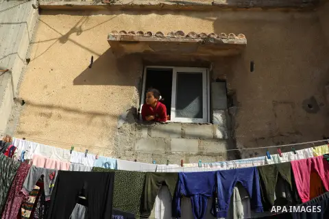 A young member of the Bakr family that lost four children, killed during the 2014 Israeli-Palestinian conflict in Gaza, looks out the window of her home in al-Shati refugee camp in Gaza City on February 7, 2021. The Inte...