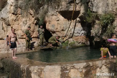 Israeli soldiers stand as Palestinians swim in the ancient spring in the West Bank village of Battir, located between Jerusalem and Bethlehem, on August 7, 2023, amid soaring temperatures. Photo by Mamoun Wazwaz