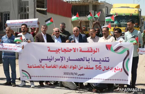 Palestinians take part in a protest against the Israeli blockade and preventing the entry of 56 items of raw materials for industry in front of the Kerem Shalom crossing in Rafah in the southern Gaza Strip on August 10,...