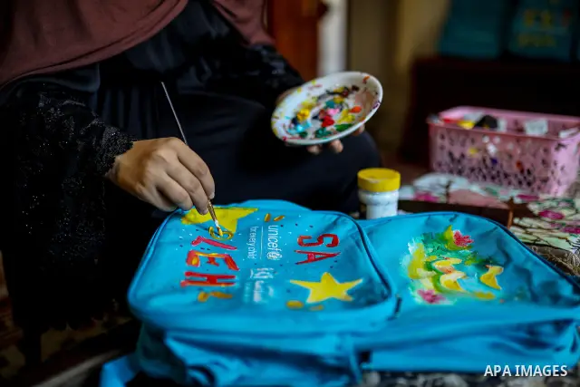 Palestinian visual artist Hala Abu Hamda, 18, paints and colors children’s bags inside her home in the al-Nasr neighborhood of Gaza City on September 27, 2026, as the new academic year begins. Students in the Gaza Strip...
