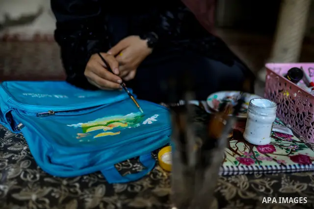 Palestinian visual artist Hala Abu Hamda, 18, paints and colors children’s bags inside her home in the al-Nasr neighborhood of Gaza City on September 27, 2026, as the new academic year begins. Students in the Gaza Strip...