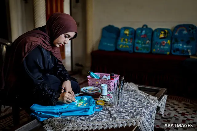 Palestinian visual artist Hala Abu Hamda, 18, paints and colors children’s bags inside her home in the al-Nasr neighborhood of Gaza City on September 27, 2026, as the new academic year begins. Students in the Gaza Strip...