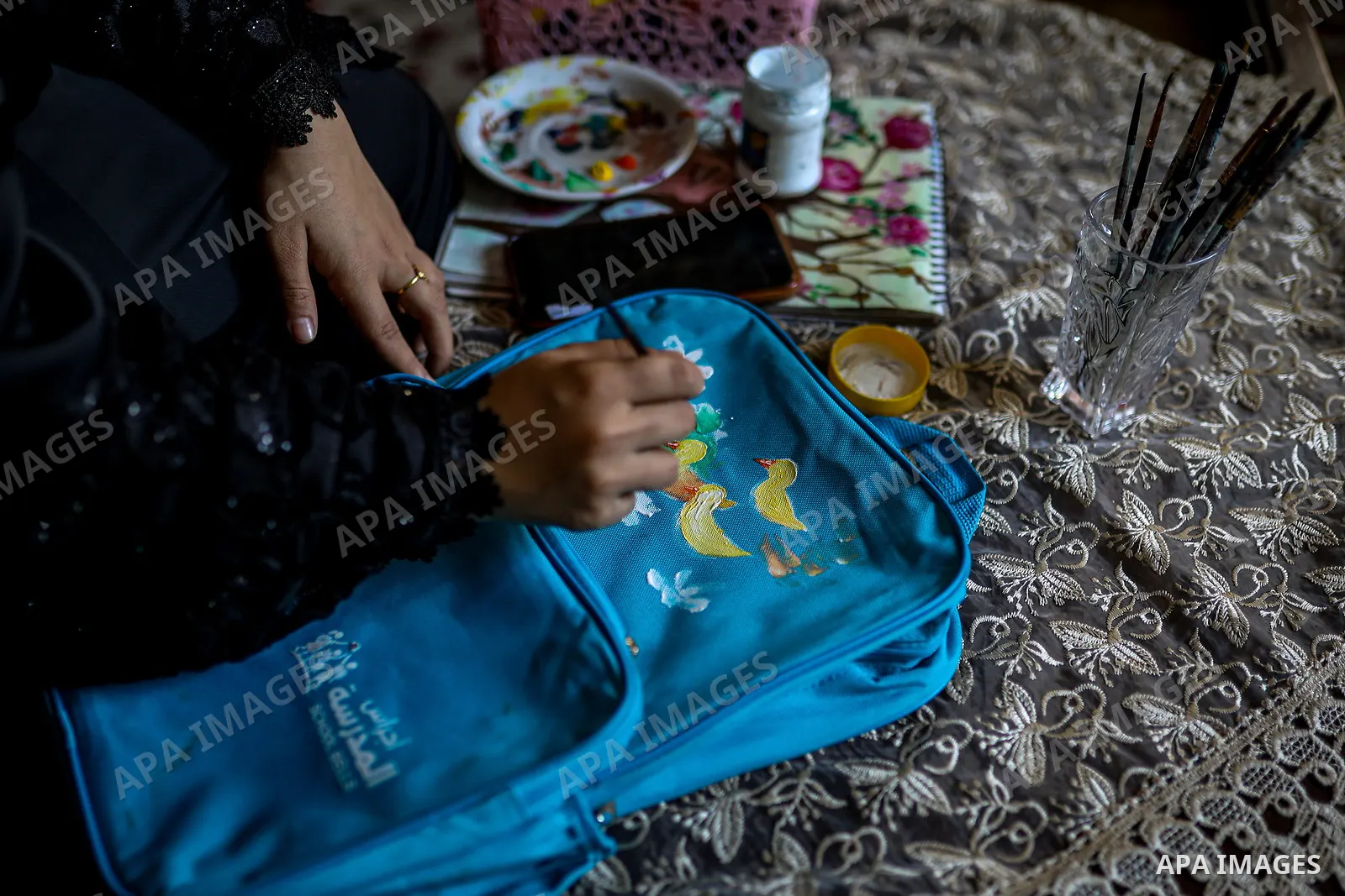 Palestinian visual artist Hala Abu Hamda, 18, paints and colors children’s bags inside her home in the al-Nasr neighborhood of Gaza City on September 27, 2026, as the new academic year begins. Students in the Gaza Strip...